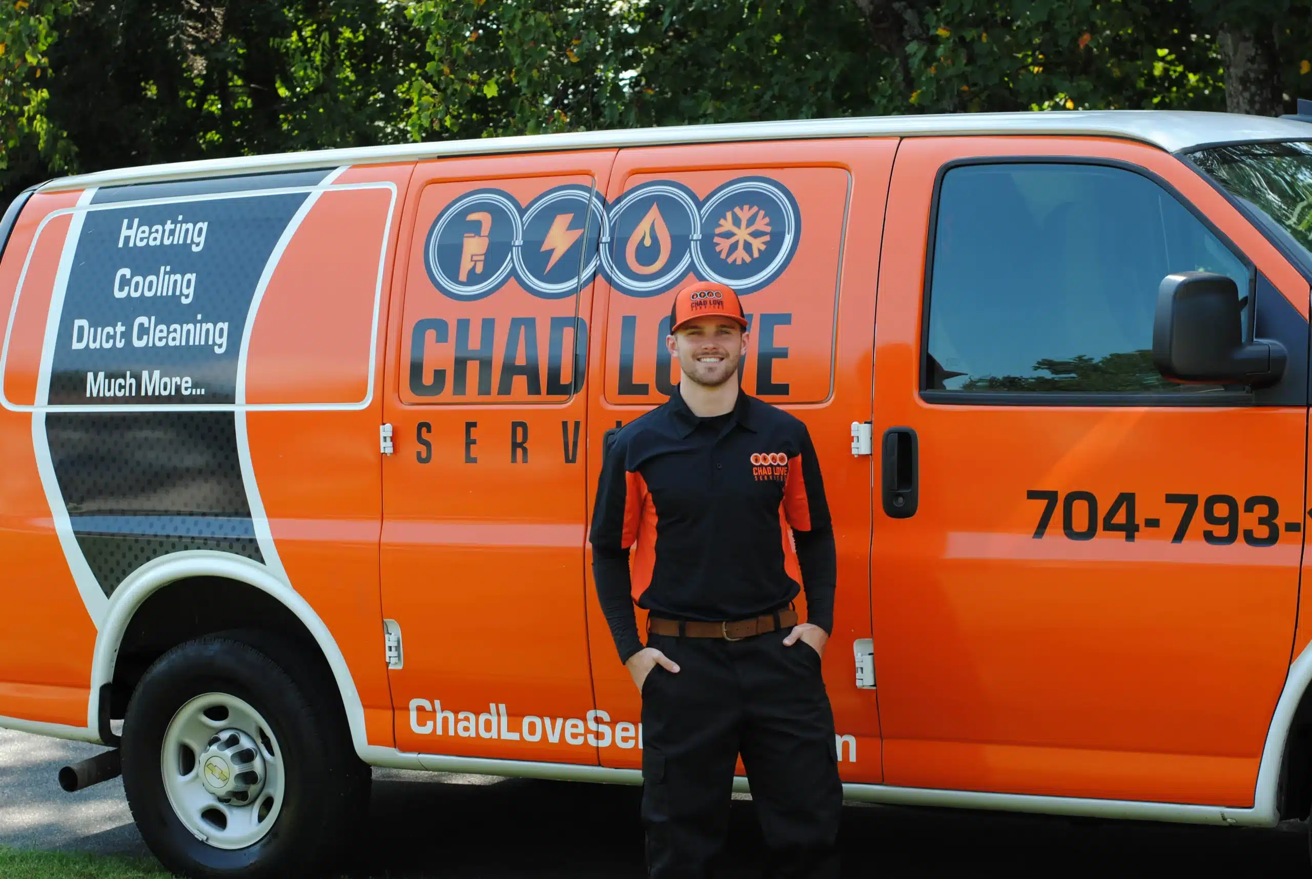 Heating technician standing beside a Chad Love Services truck in Charlotte, NC