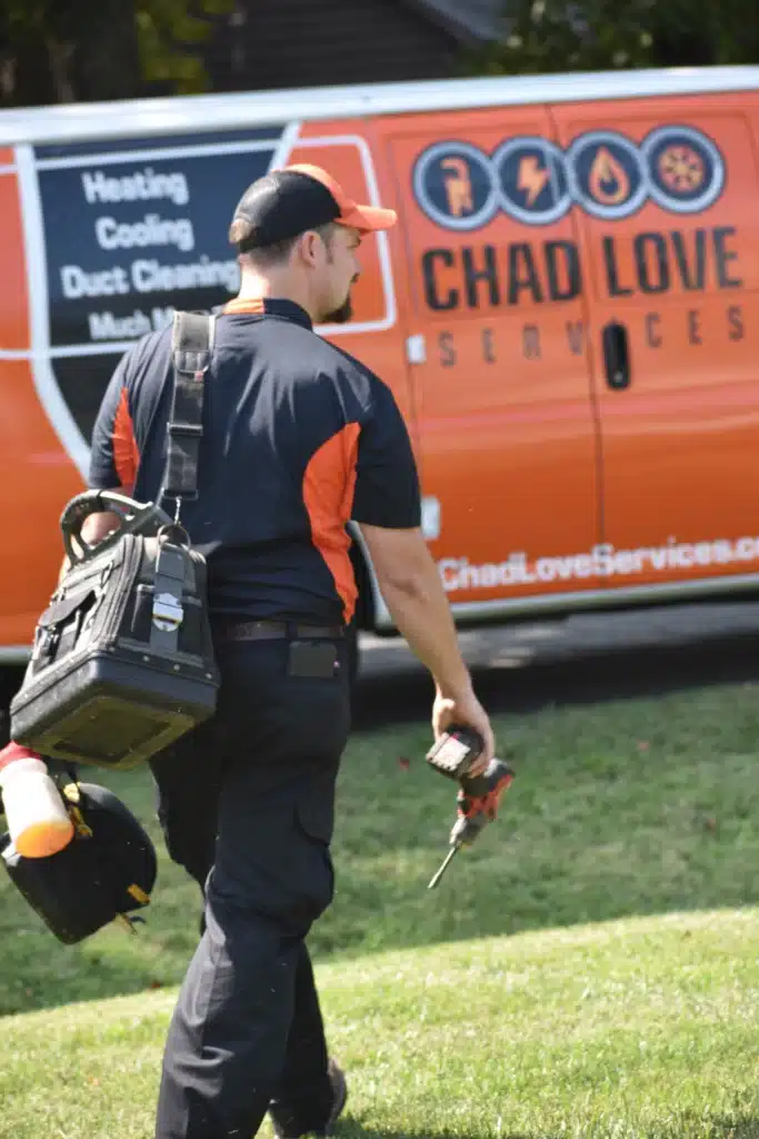 Chad Love Services tech walking with tools in front of work van in Charlotte